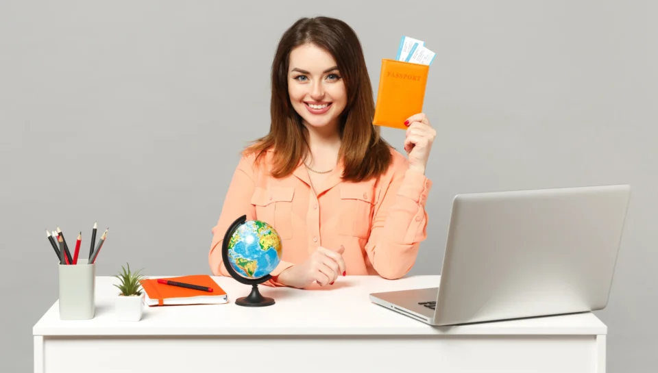 young-smiling-woman-holding-earth-world-globe-passport-boarding-pass-ticket-work-desk-with-pc-laptop-isolated-gray-background-achievement-business-career-lifestyle-concept-mock-up-copy-space